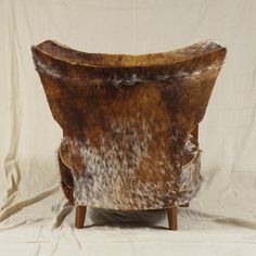 a cowhide chair with wooden legs on a white background