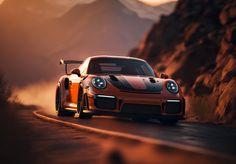 an orange sports car driving down the road in front of some mountains and rocks at sunset