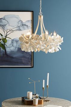 a white chandelier hanging from the ceiling in a dining room with blue walls