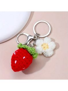 a crocheted strawberry keychain with a white flower on the front and side