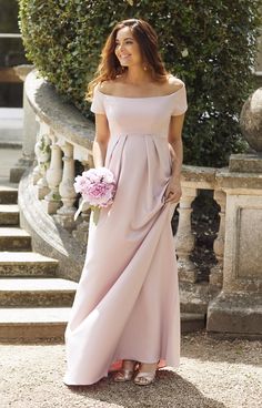 a woman in a long pink dress is standing on some steps and smiling at the camera