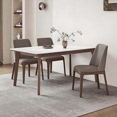 a dining room table and chairs in front of a white wall