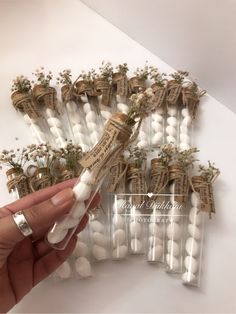 a person is holding up some white candles with flowers on them and wrapped in twine