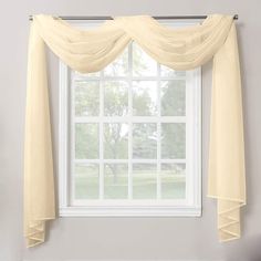 a window with white sheer curtains hanging from it's side