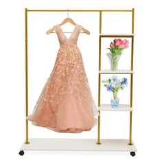 a dress hanging on a rack with flowers and vases in front of the rack