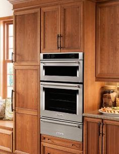 an oven built into the side of a cabinet in a kitchen with wooden cabinets and drawers