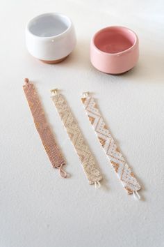 three different types of bracelets sitting on a table next to a bowl and cup