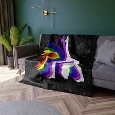 a couch with a blanket on top of it in front of a green wall and wooden floor