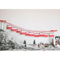 a red and white train traveling down tracks next to snow covered ground with buildings on each side