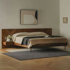 a bed sitting on top of a hard wood floor next to a wall mounted painting