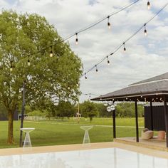 an outdoor patio with string lights and tables in the foreground on a cloudy day