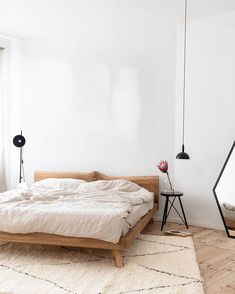 a bed sitting in a bedroom on top of a wooden floor next to a window