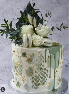 a white and green decorated cake with flowers on the top is sitting on a table