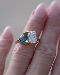 a woman's hand holding an engagement ring with two blue and white stones on it