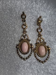 Add a touch of vintage glamour to your look with these antique goldtone door knocker earrings. The oval-shaped earrings feature a bezel setting with cabochon pink stones and imitation pearls. The dangle drop style adds a touch of elegance to any occasion, whether it's Mother's Day, an engagement, wedding, graduation, Christmas, anniversary, Father's Day, birthday, christening, confirmation/communion, or Valentine's Day. These earrings are handcrafted with brass and have a push-on style closure. Vintage Teardrop Nickel-free Clip-on Earrings, Vintage Nickel-free Teardrop Clip-on Earrings, Nickel-free Teardrop Vintage Clip-on Earrings, Vintage Teardrop Metal Earrings, Pink Metal Jewelry With Vintage Charm, Victorian Dangle Clip-on Earrings, Vintage Pink Nickel-free Earrings, Elegant Pink Drop Plug Earrings, Vintage Pink Metal Earrings