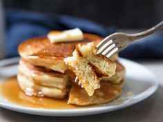 a stack of pancakes on a plate with syrup and butter being drizzled over them