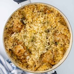 a pan filled with chicken and rice on top of a stove burner next to a blue towel