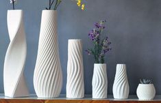 five white vases with flowers in them on a shelf