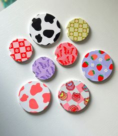 six buttons with different designs on them sitting next to each other in front of a white surface