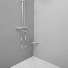 a shower head and hand rail in a bathroom with gray walls, tile flooring and white fixtures