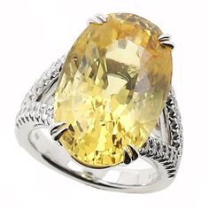 This yellow sapphire and diamond ring has a 19.73 oval shape center yellow sapphire that is GIA certified and a total carat weight of 0.60cts in a split shank semi mounting made of 14 karat white gold. R896-YSA14W Fine Yellow Oval Sapphire Ring, Luxury Yellow Oval Sapphire Ring, Yellow Oval Sapphire Diamond Ring, Yellow Oval Brilliant Cut Diamond Ring, Oval Yellow Sapphire Ring With Diamonds, Yellow Oval Diamond Ring Fine Jewelry, Yellow Oval Diamond Ring, Fine Jewelry, Fine Jewelry Yellow Oval Diamond Ring, Oval Yellow Sapphire Ring With Center Stone