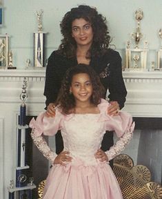 two women standing next to each other in front of a fireplace