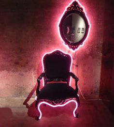 a chair sitting in front of a mirror with lights on it's back legs