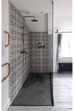 a bathroom with black and white tiles on the walls, shower head and hand held faucet