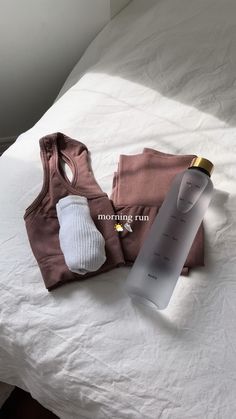 a bottle of water and some clothes on a bed