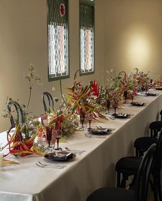 a long table is set up with place settings and flowers in vases on it