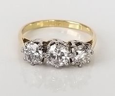 three stone diamond ring in yellow gold and white gold with diamonds on the sides,