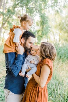 a man and woman holding a baby in their arms while standing next to each other