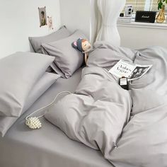 an unmade bed with grey sheets and pillows