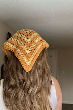 a woman with long hair wearing a crocheted hat in yellow and orange colors