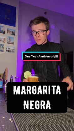 a man standing at a bar with a drink in his hand and the words margarita negra on it