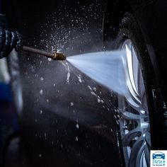 a person is spraying water on the wheel of a car with a hose attached to it