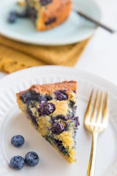 a slice of blueberry pie on a plate with a fork next to the rest of the cake