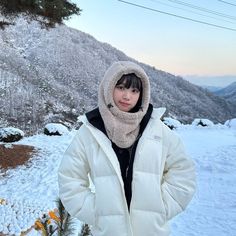 a woman standing in the snow with her hands on her hips wearing a white jacket