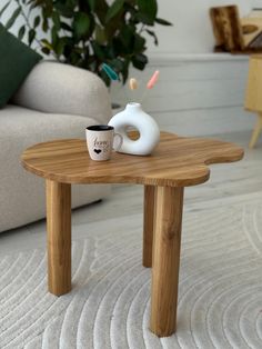 a coffee table with a white vase on it and a cup sitting on top of it