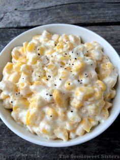 a white bowl filled with macaroni and cheese on top of a wooden table