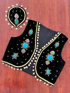 two pieces of black velvet with blue and white beadings on top of a wooden floor