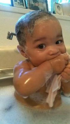 a baby sitting in a sink covered in soap