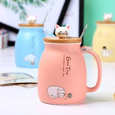 a pink coffee mug with two cats on the top and one has a toothbrush in it