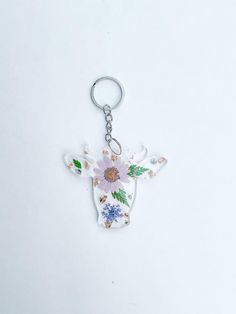 a cow with flowers on it's head is shown in the shape of a keychain