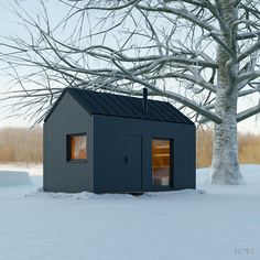 a small black building sitting in the middle of a snow covered field next to a tree