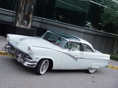 an old white car parked in front of a building