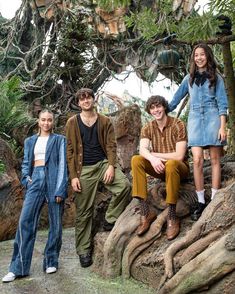 four young people are posing for a photo in front of trees and rocks at the zoo