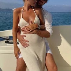 a man and woman are hugging on a boat in the ocean while wearing white swimsuits