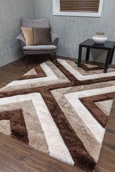 a brown and white rug on top of a wooden floor next to a gray chair