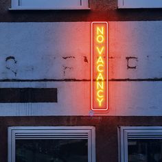 a neon sign on the side of a building that says no vacany in front of it